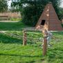 Diamond net climbing structure with wooden posts on a playground.